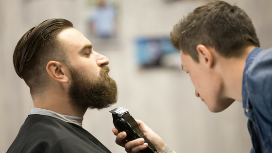 Young Man grooming his beard by barber