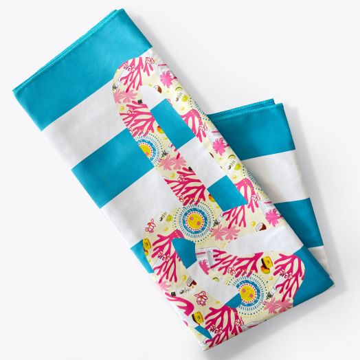 A folded beach towel with blue and white stripes, featuring a large peace sign design decorated with colorful coral and sea-themed patterns.