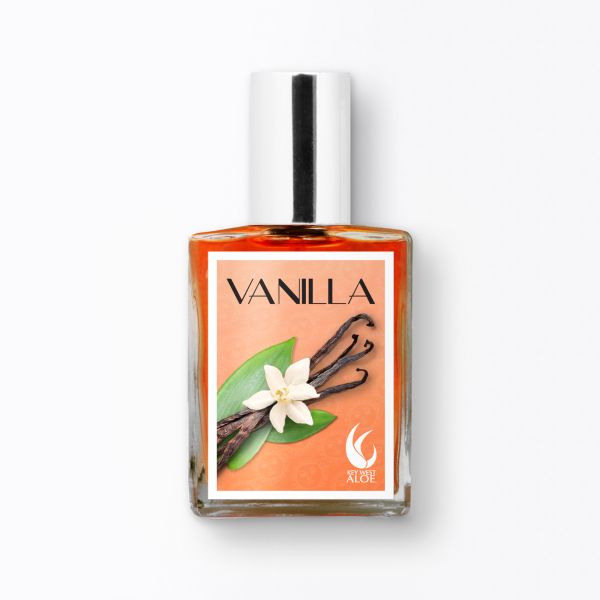 Clear glass bottle of vanilla fragrance with a silver cap, featuring an orange label with black text reading "VANILLA," a white flower, vanilla pods, and green leaves.
